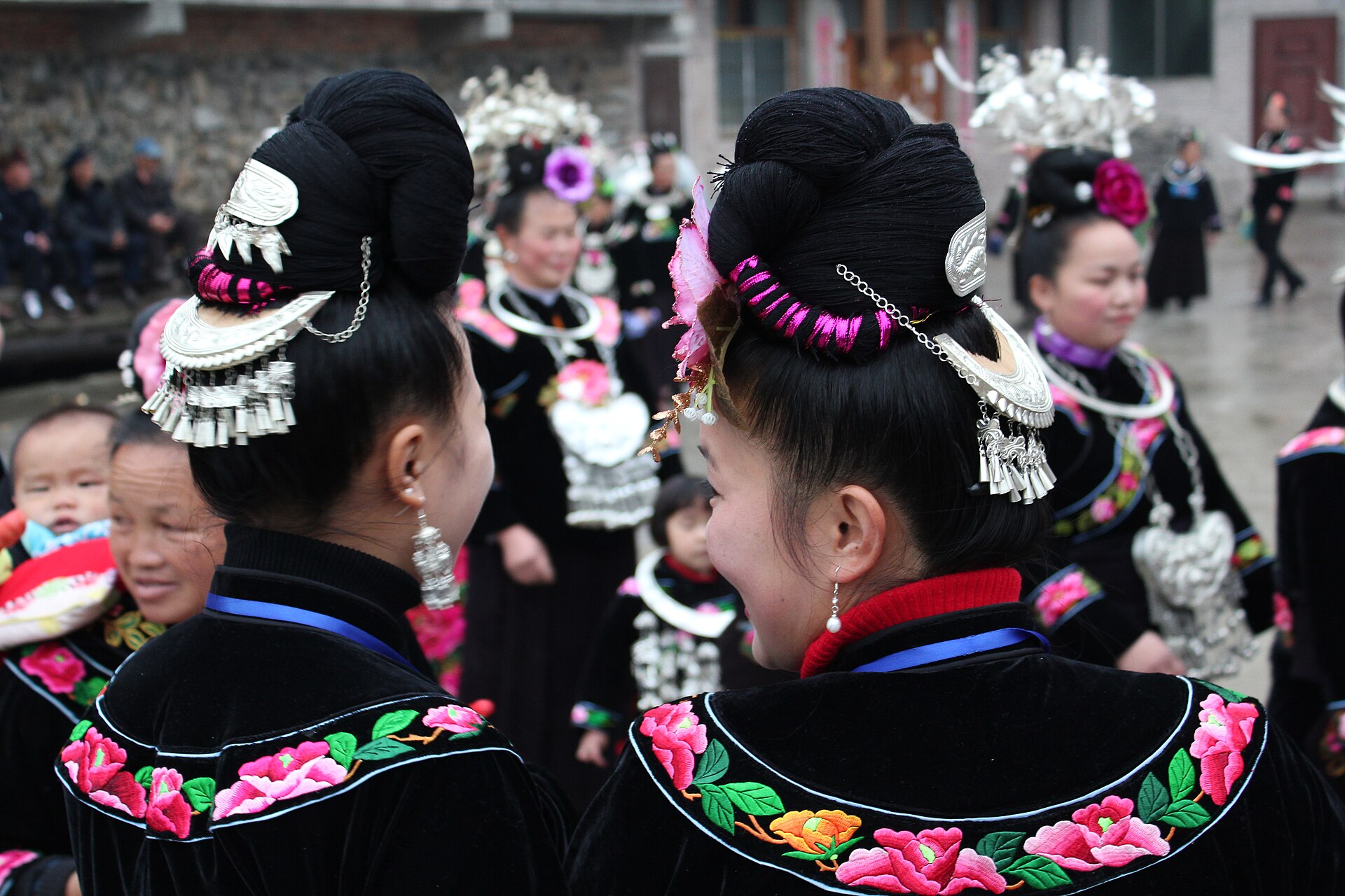 Mujeres miao con tocado de plata y traje bordado durante una fiesta en Guizhou